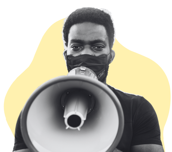 A black and white image of a dark skin young man wearing a cloth mask covering his nose and mouth facing forward with a megaphone to his mouth.