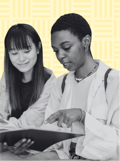 A black and white image of two women looking down and pointing at an open book.